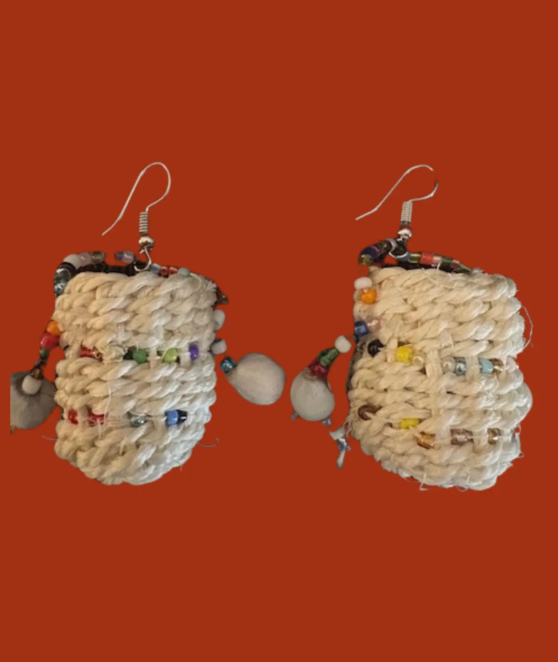 Handmade woven earrings with colorful beads on orange background