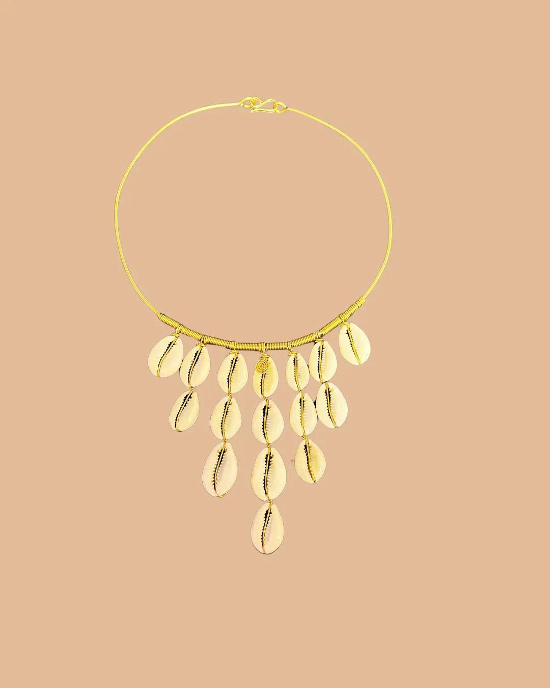 Gold necklace with dangling cowrie shells on minimalist background