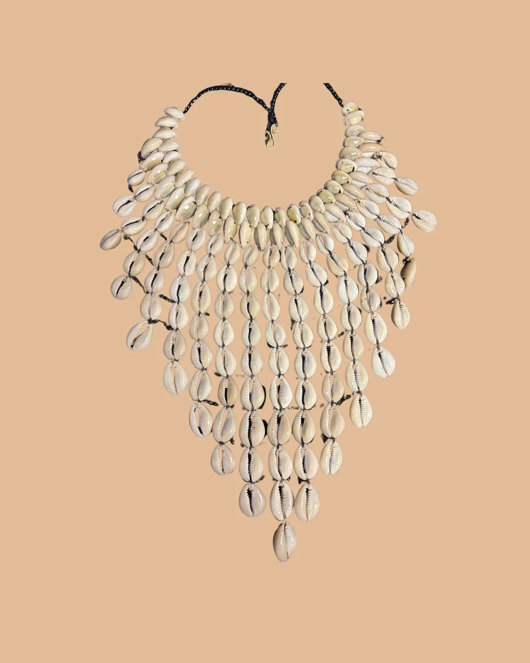 Elaborate statement necklace made of white cowrie shells on beige background