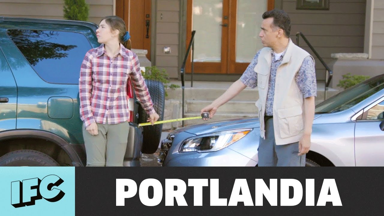 Woman and man holding a measuring tape stretched between two parked cars in front of a house, with IFC and PORTLANDIA text below.