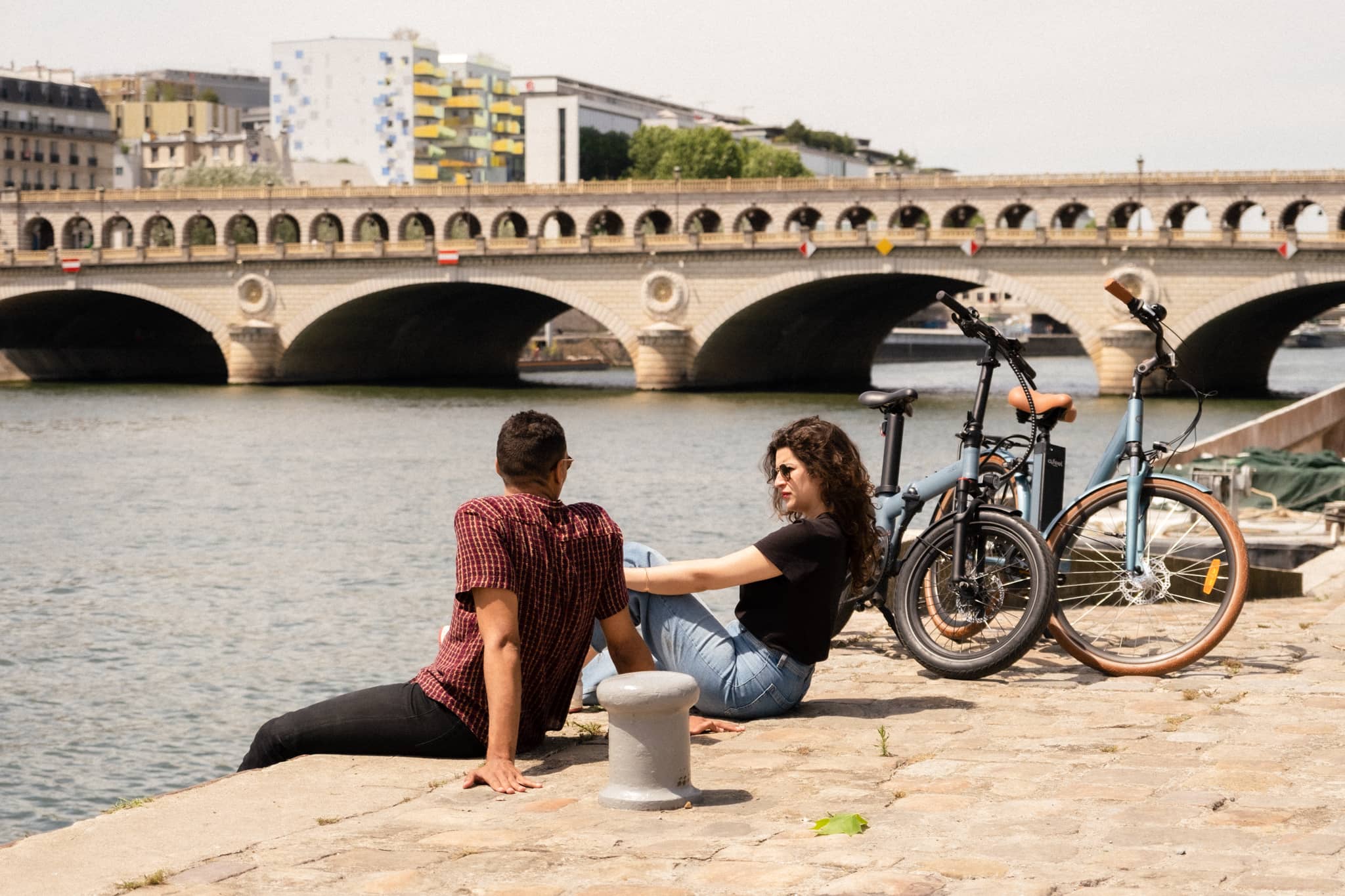 Un homme et une femme assis au bord de l'eau à côté de leur vélo