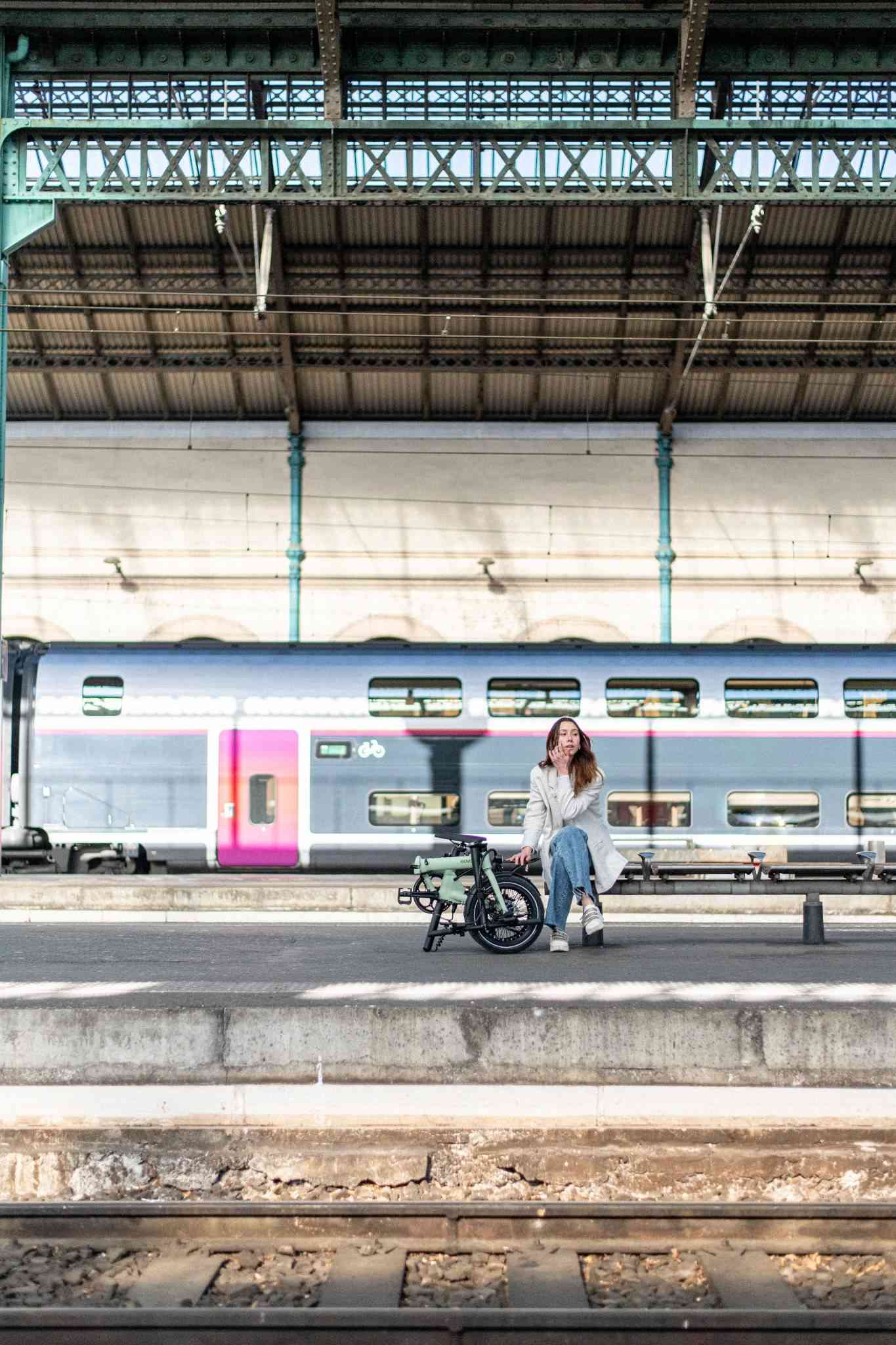 salariée avec son vélo de fonction eovolt plié à la gare