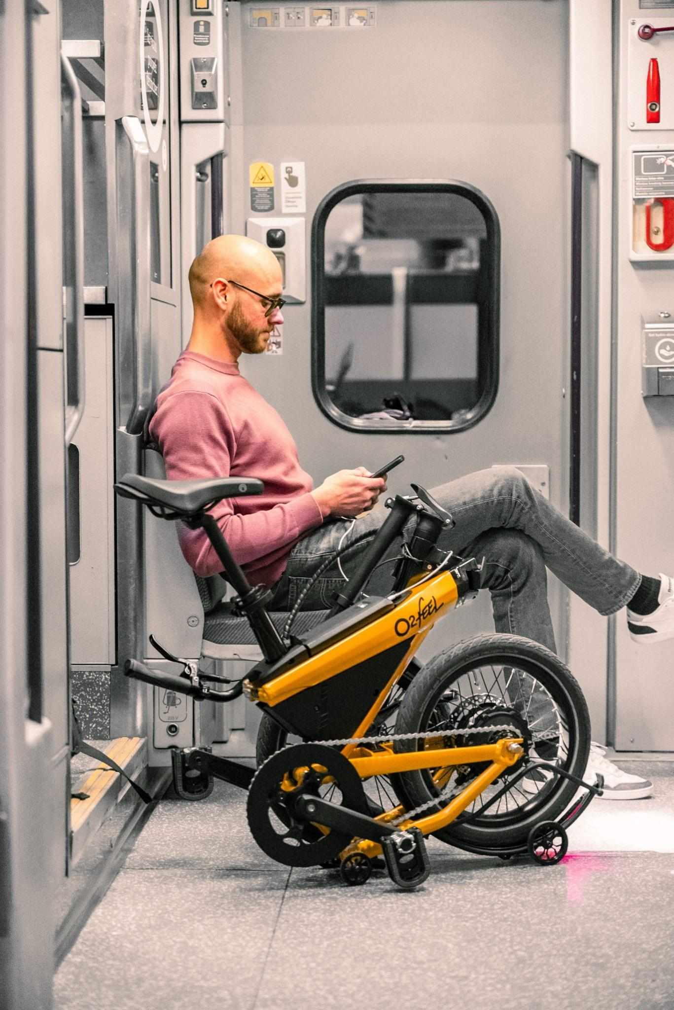 Employé assis dans un train avec son vélo pliant Jim O2Feel – solution vélo de fonction