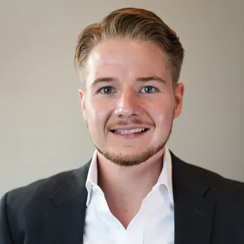 A man wearing a suit and tie smiling for the camera.