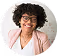 Smiling woman with curly hair and glasses wearing headset and light pink blazer.