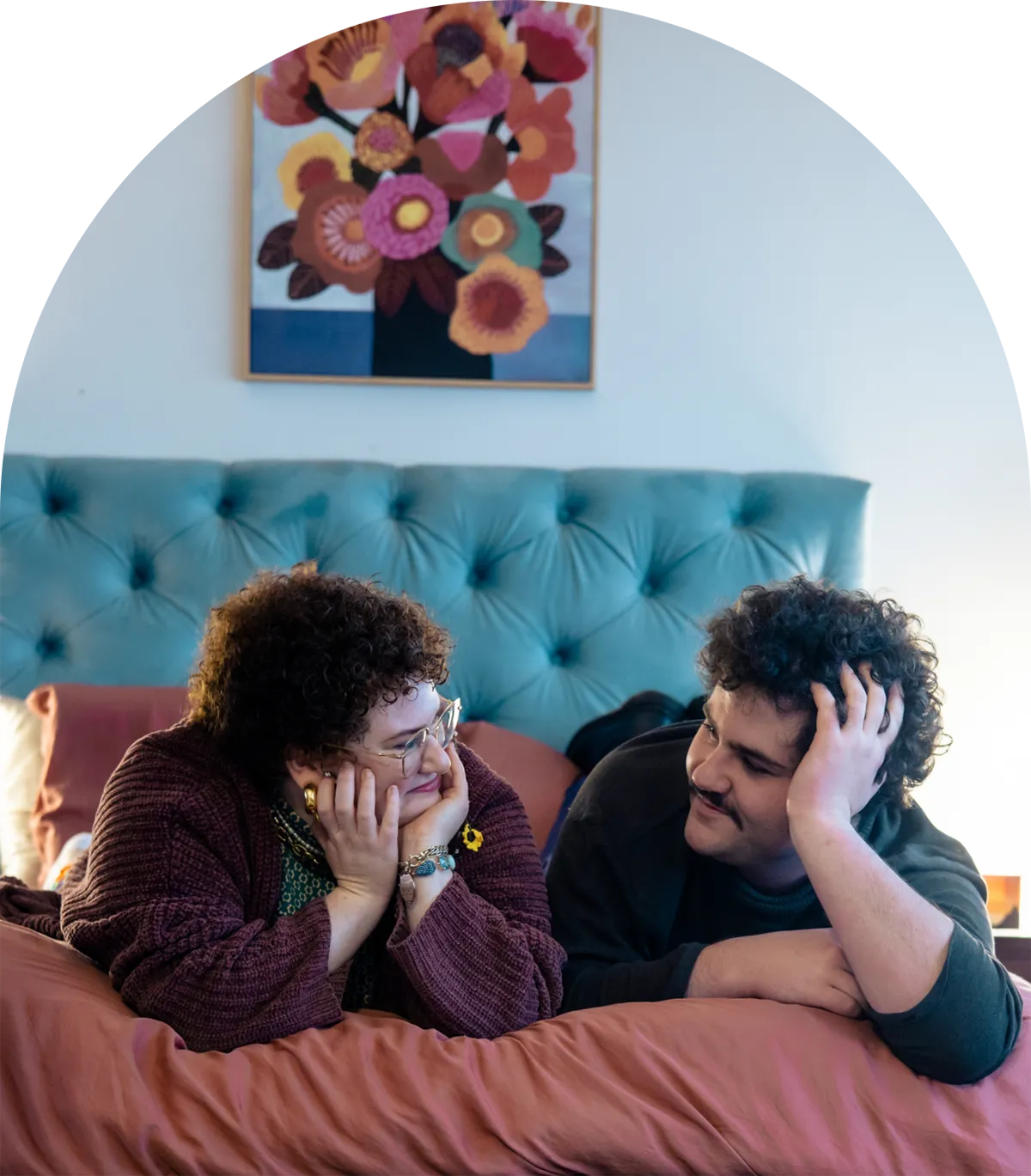 A photo of Emilia and their partner lying on their bed
