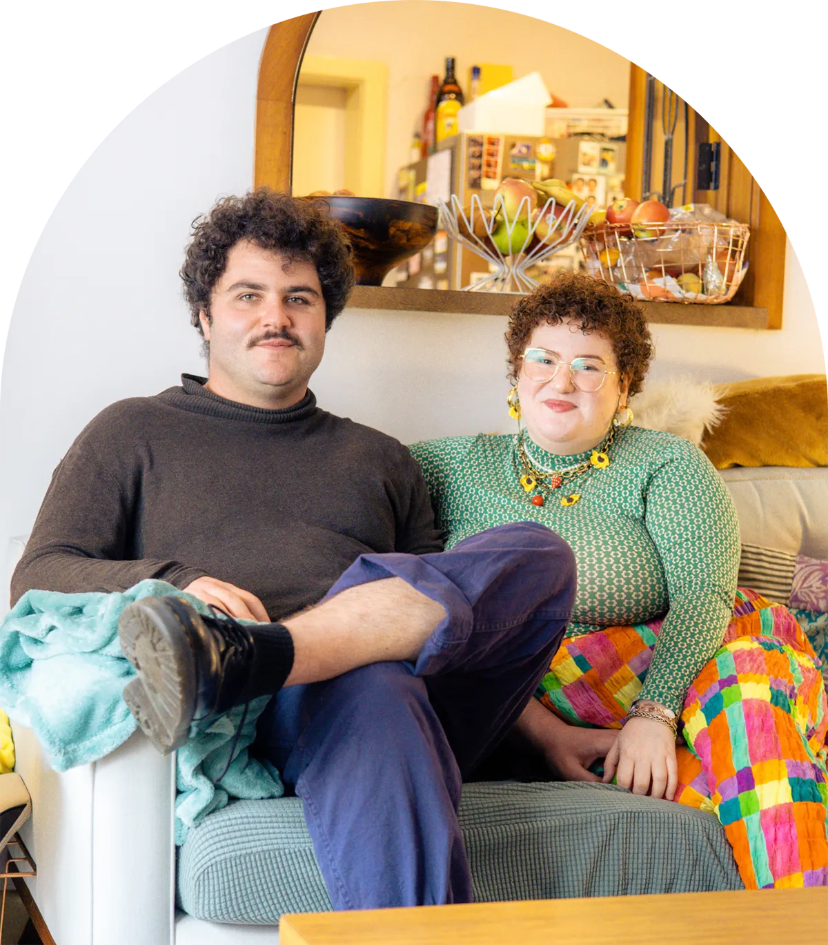 A photo of Emilia and their partner sitting on their couch