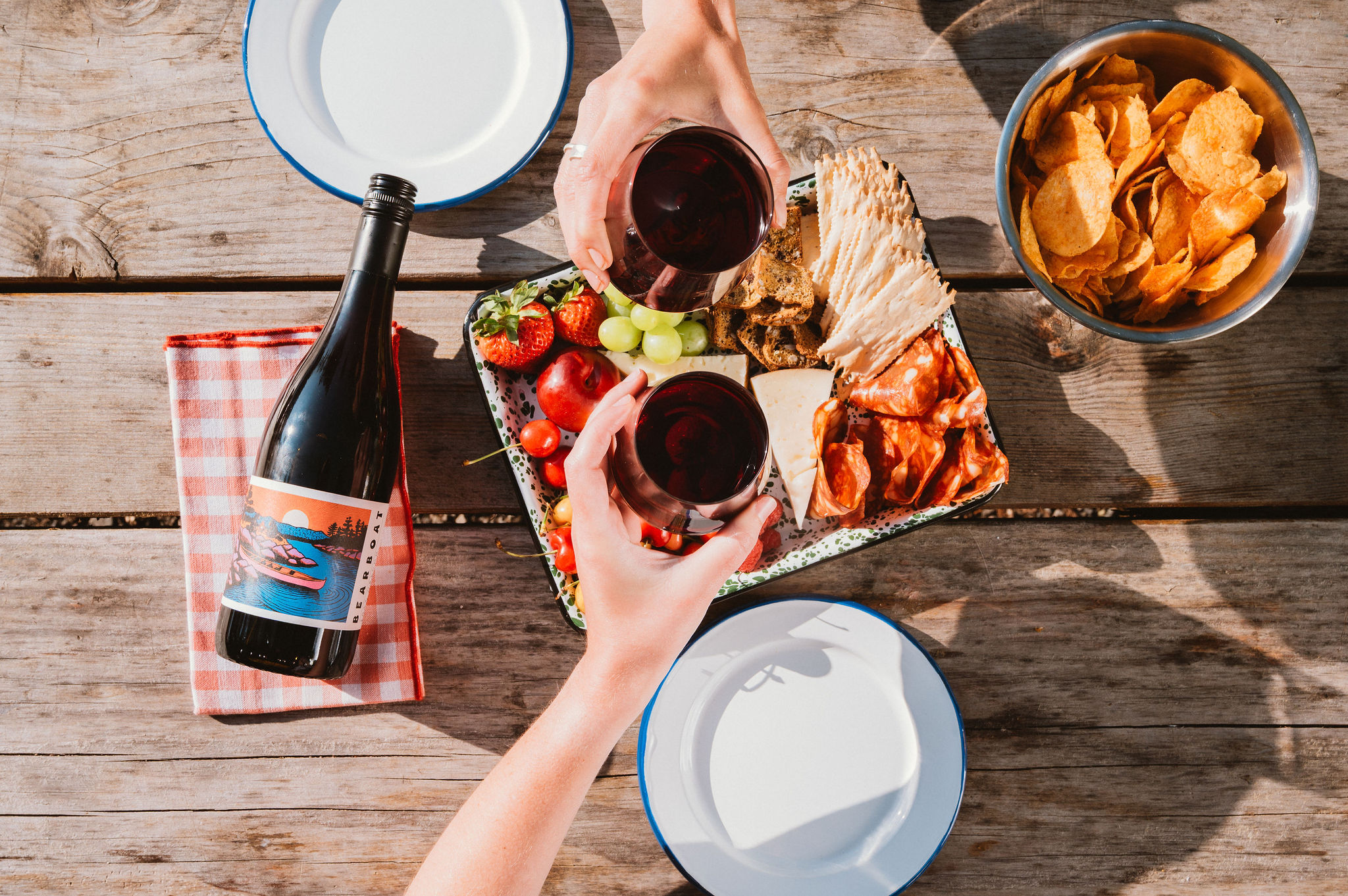 A table set outdoors for a casual dinner, with a bottle of Bearboat Pinot Noir alongside the food