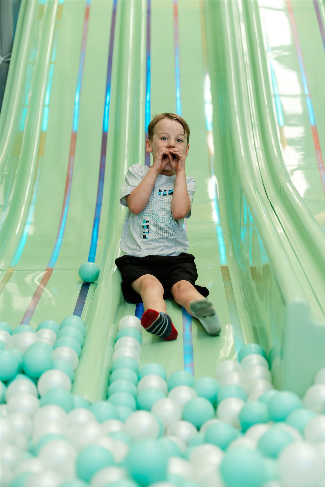 Children enjoying indoor playground tube slide ride.