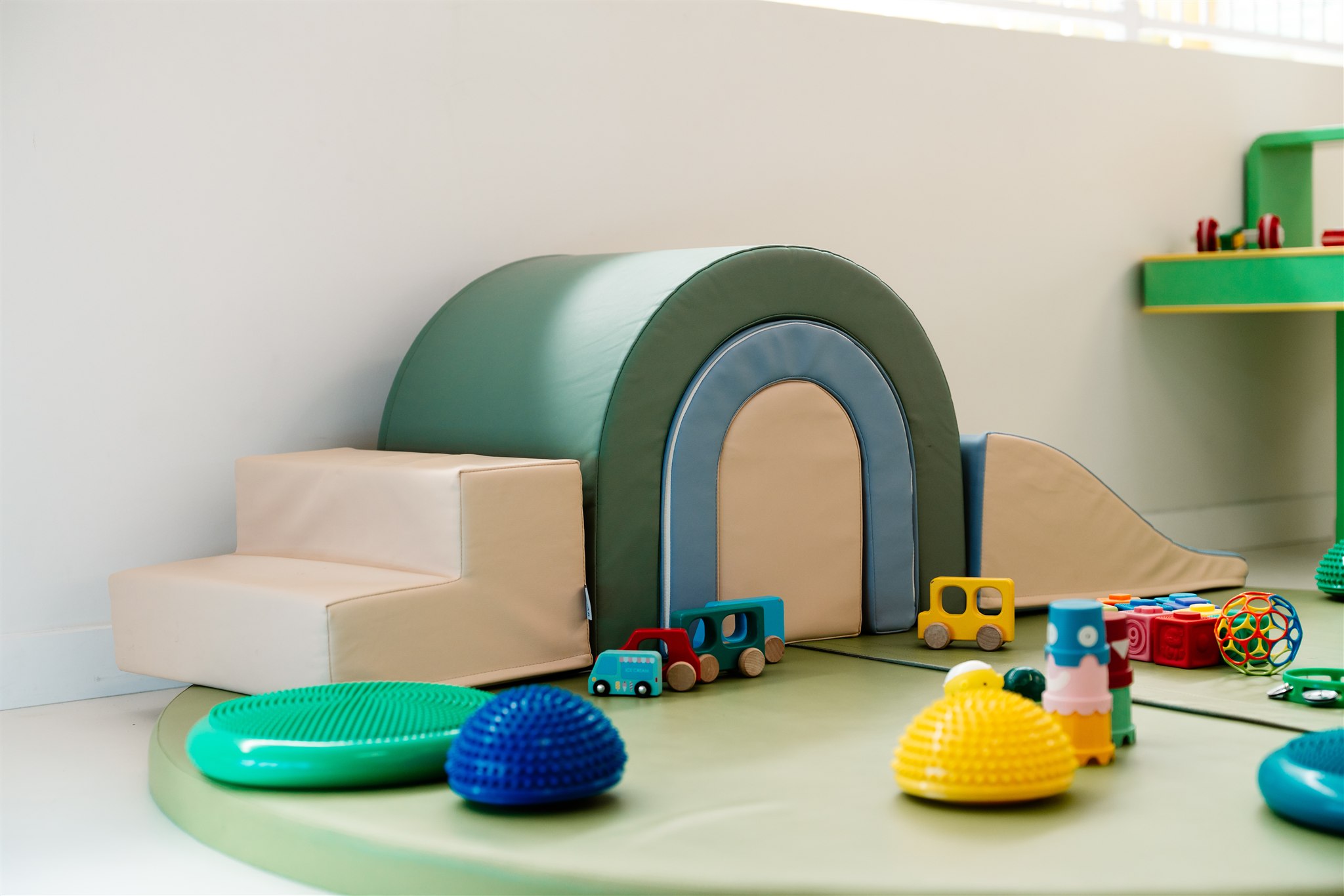 Child playing in colorful indoor playground, smiling and swinging, wearing a striped shirt.