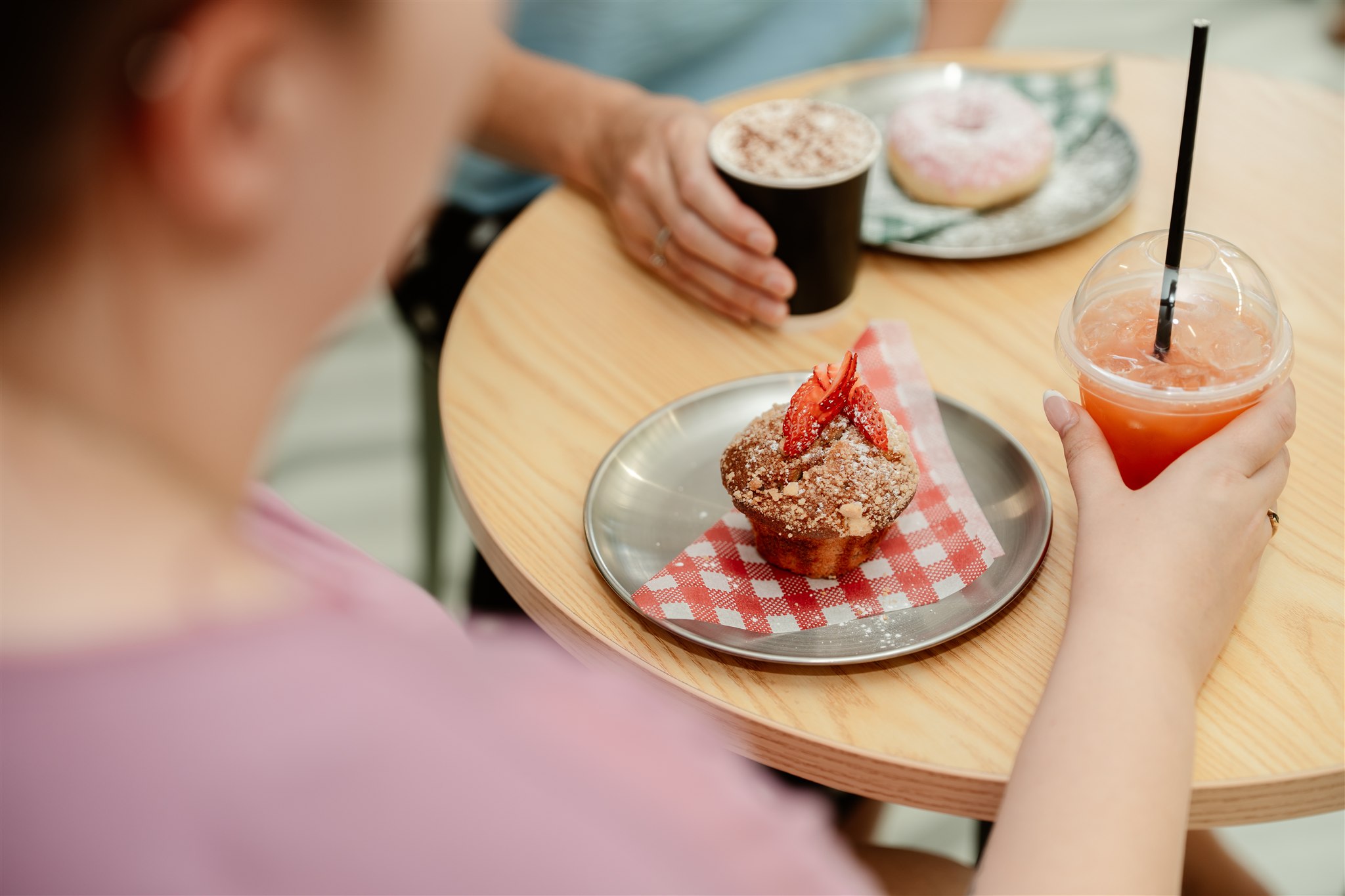 Smiling woman enjoying coffee in a cafe, wearing striped shirt.