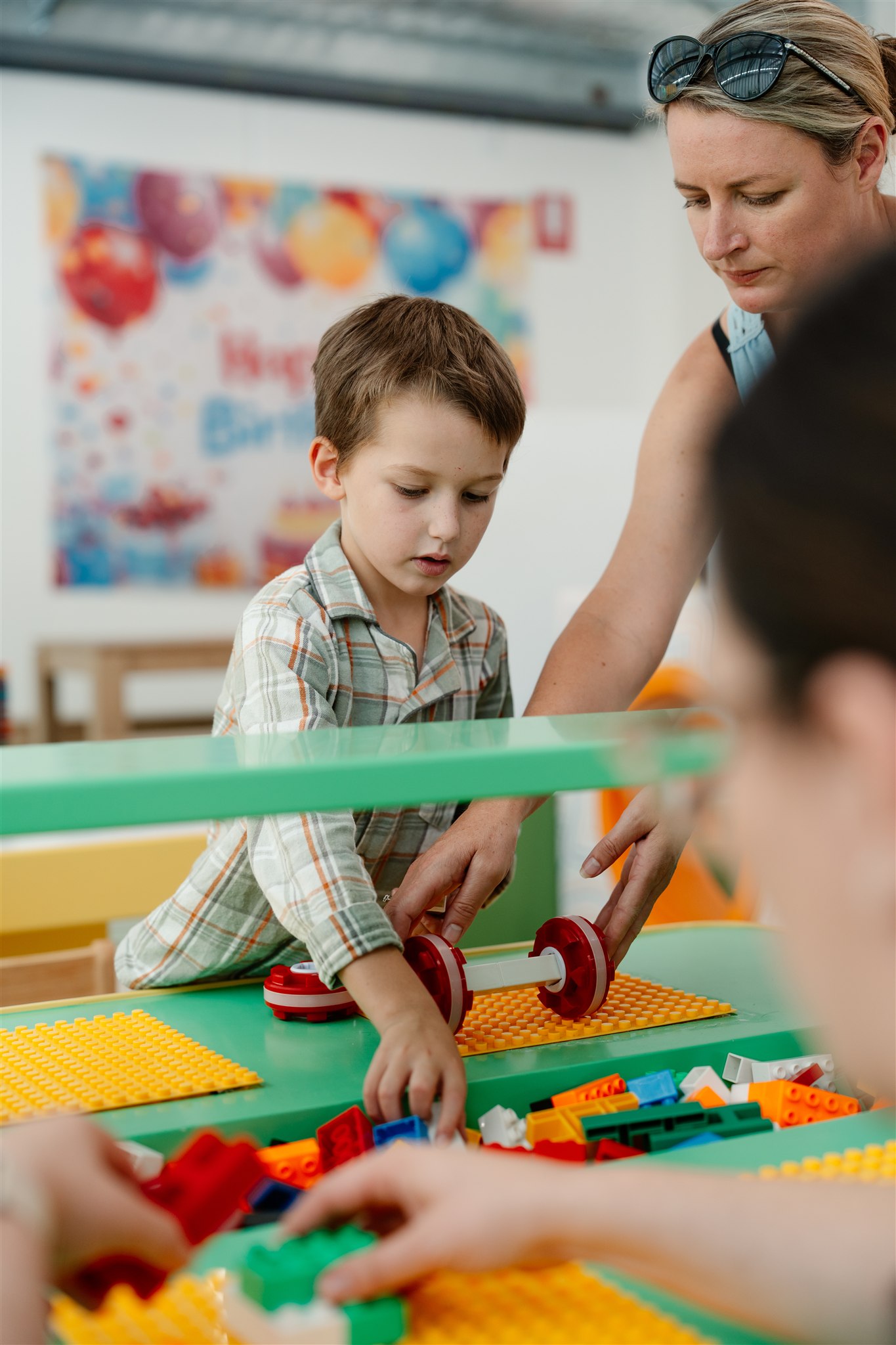 Teacher playing with child using colorful ball in vibrant classroom environment.