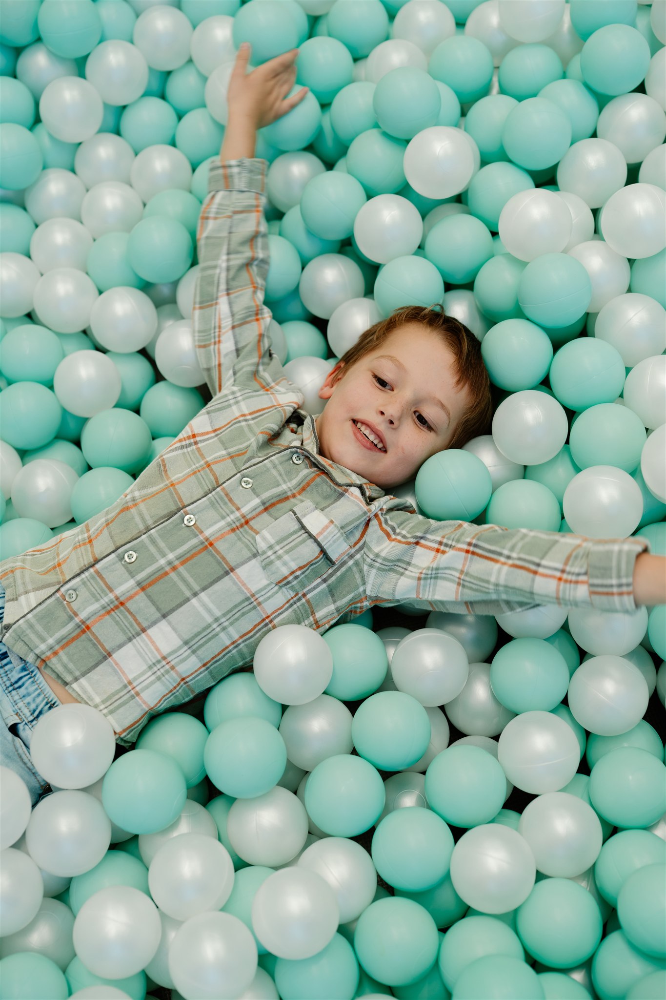 Child playing in colorful ball pit, smiling and having fun.