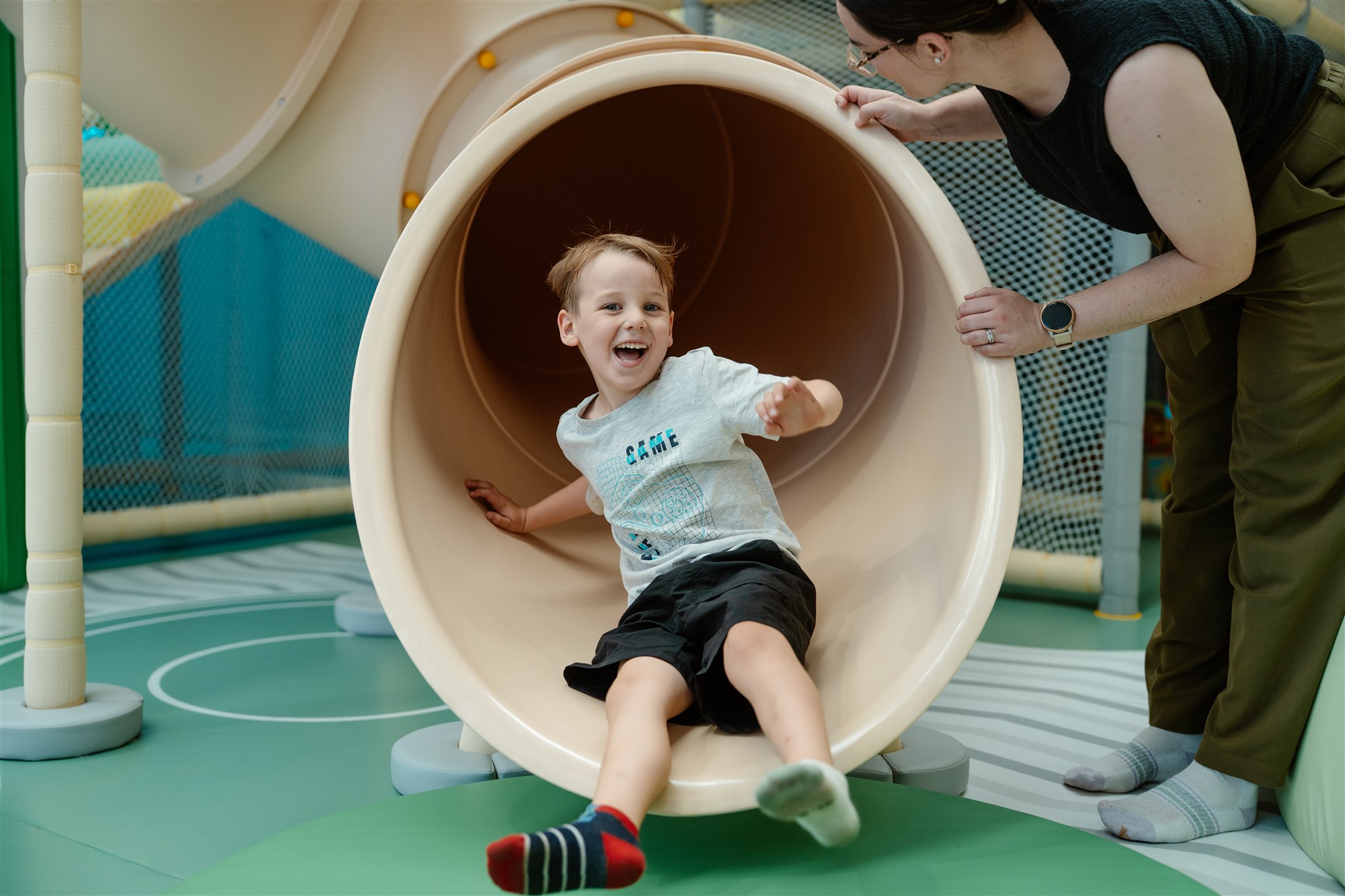 Child playing happily in a colorful ball pit at an indoor playground.