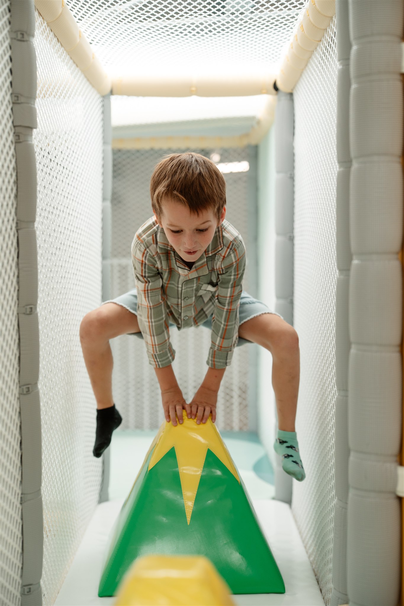 Child playing in colorful ball pit, indoor playground fun.