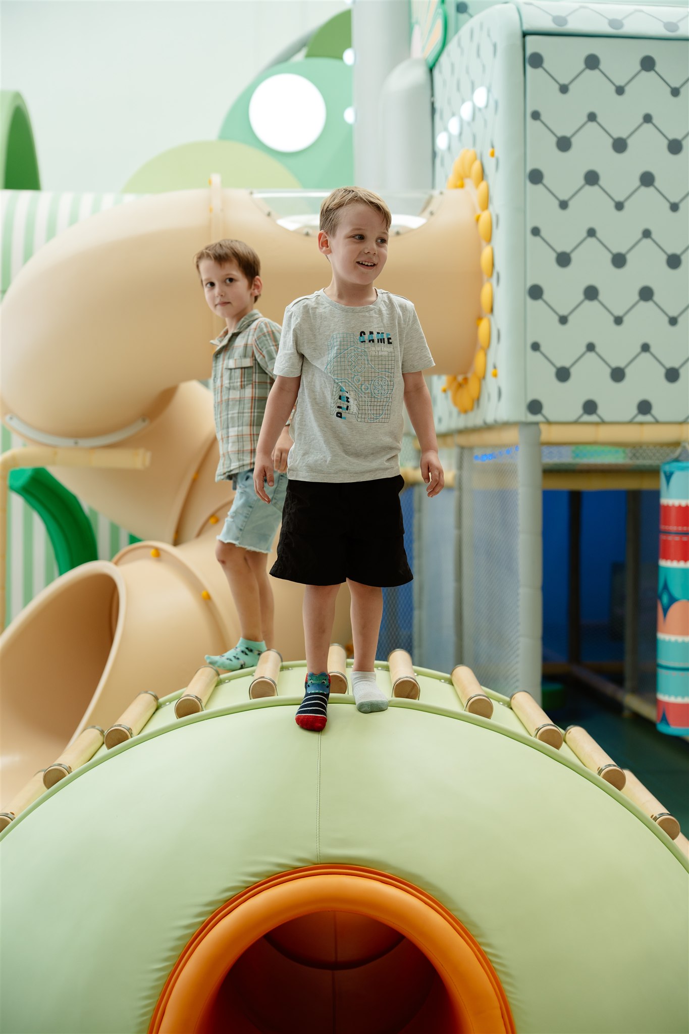 Baby playing with colorful balls on orange mat, wearing blue pajamas.