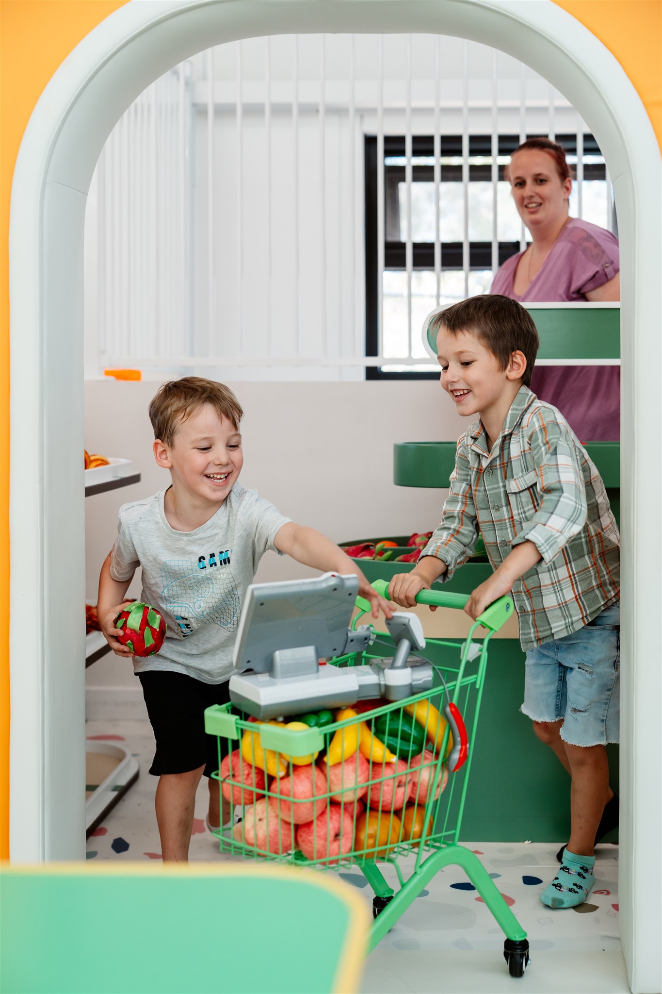 Child playing joyfully in a colorful ball pit at an indoor playground.