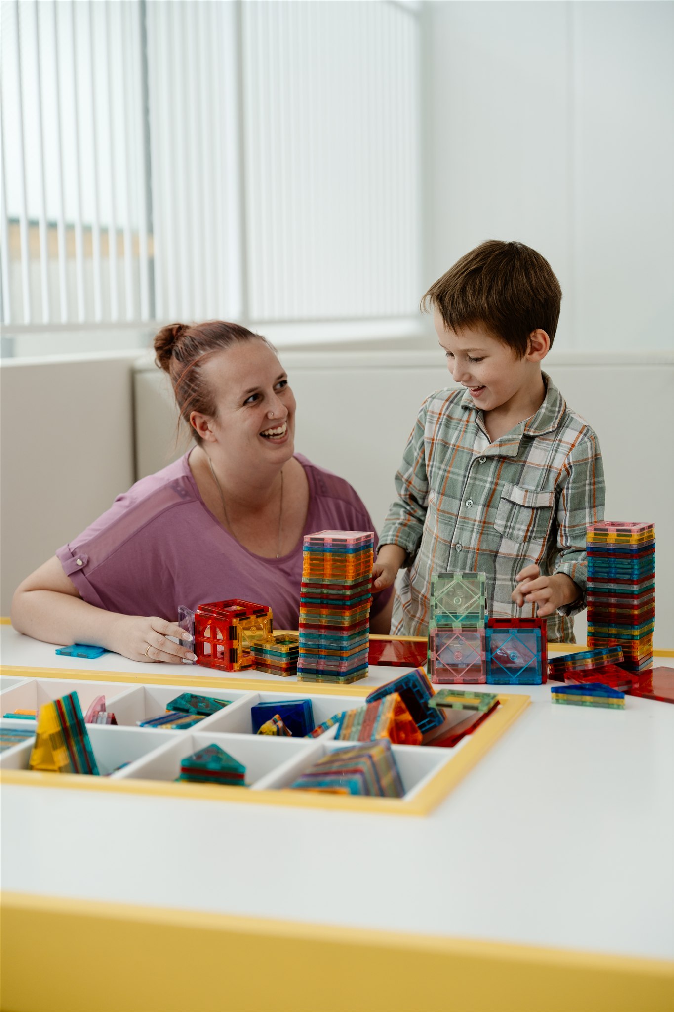 Child playing in colorful ball pit with joyful expression.