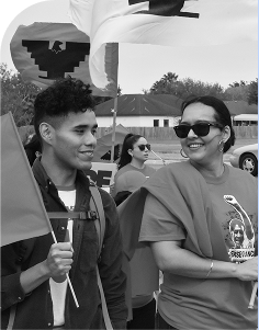 Community organizers participate in a social justice march, holding flags and advocating for immigrant justice and equity.