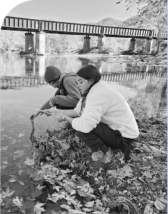 Two Tides-supported environmental advocates gather water samples from a river, driving grassroots efforts in ecological justice and sustainability.