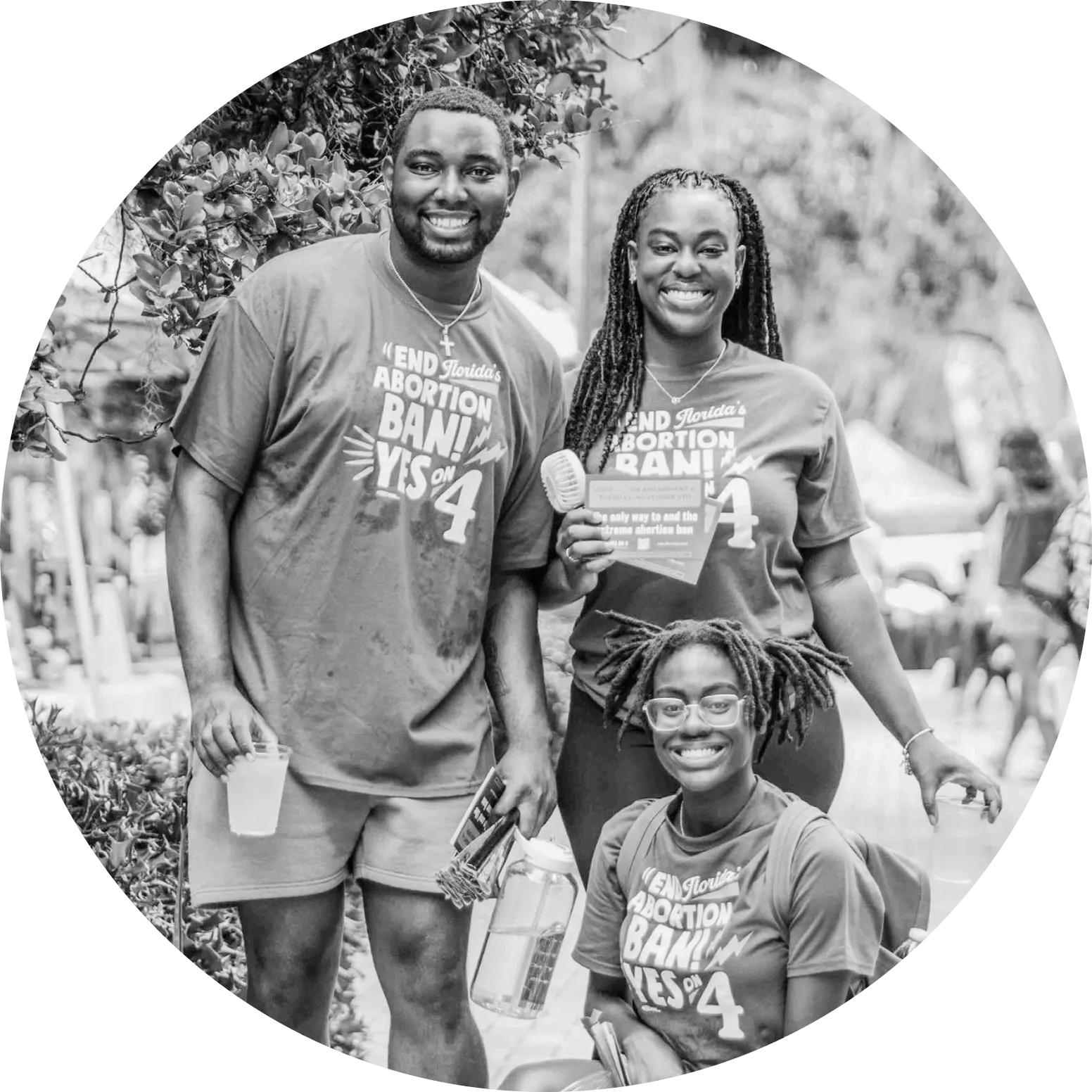 Group of three smiling Floridians—two standing and one seated—wearing "End Floridas Abortion Ban Yes on 4" shirts to advocate for reproductive freedom.