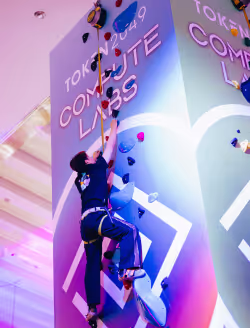 person climbing a rock climbing wall with promotional material on it