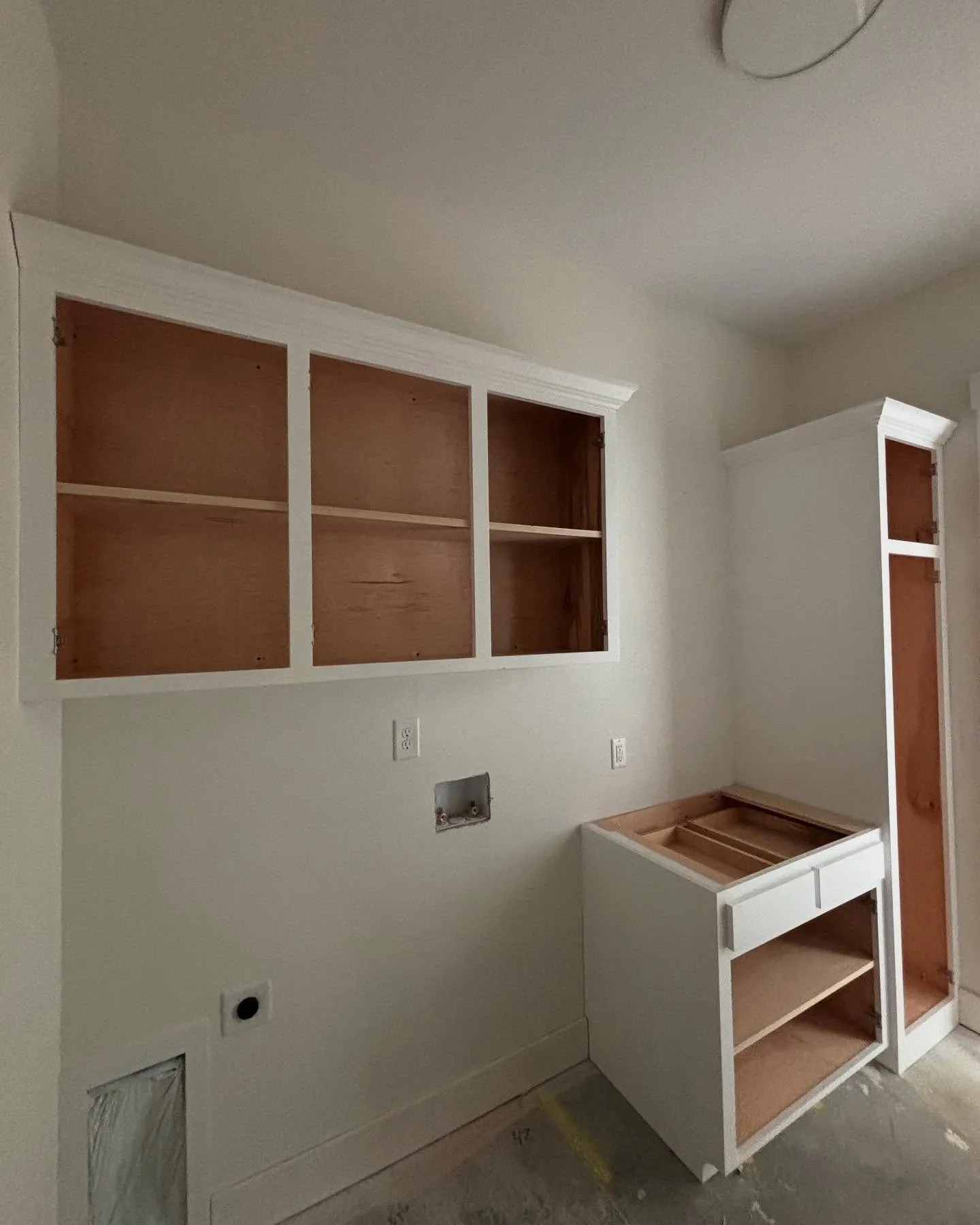 New cabinets installed in a laundry room as part of a home construction project by Lee Brothers Construction in Greenville, NC.