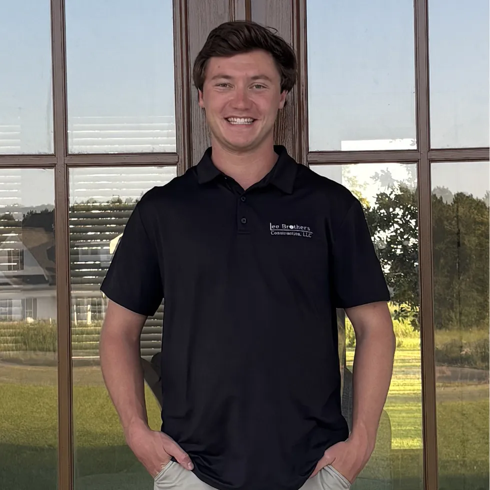 Joe Lee, founder of Lee Brothers Construction headshot, smiling in front of a new home construction
