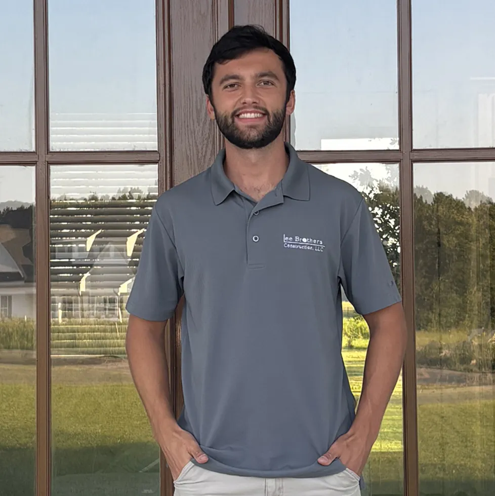 Jake Lee, founder of Lee Brothers Construction headshot, smiling in front of a new home construction