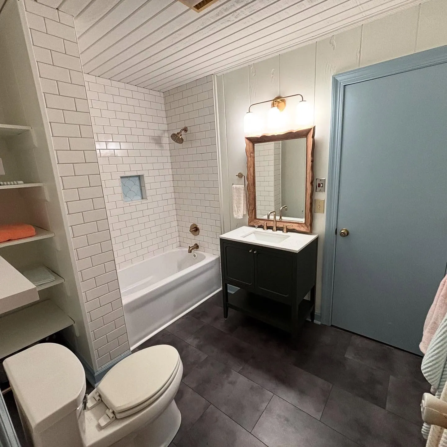 A bathroom that has been remodeled by Lee Brothers Construction with a new bathtub, sink, and flooring