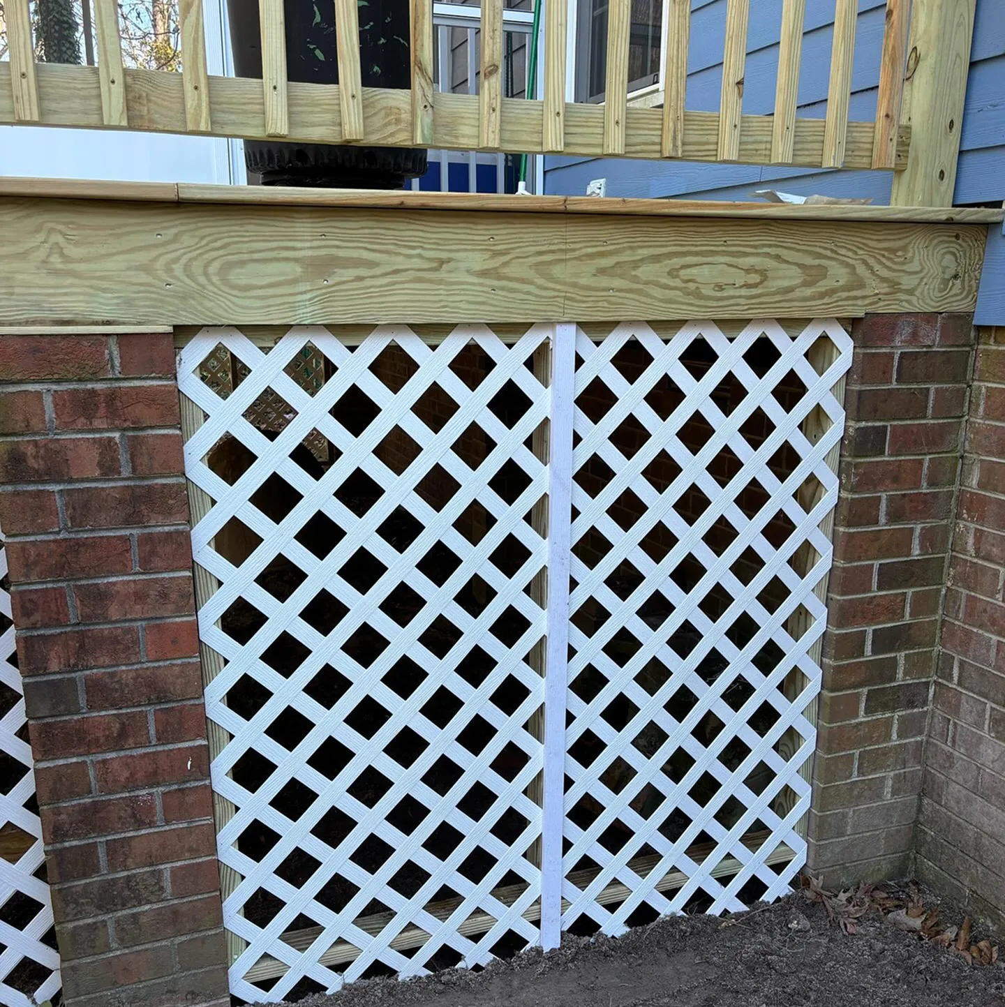 A deck that has been repaired with lattice and a new railing