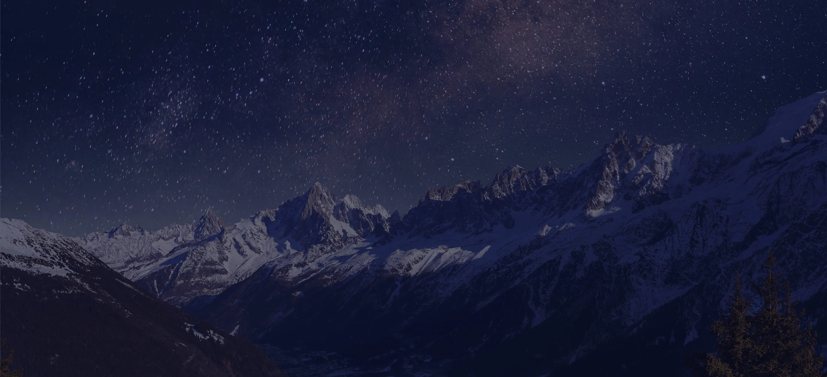 Snow-covered mountain range under a clear starry night sky.