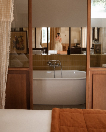 A view of the stylish private bathroom at Maison Roz in Brittany, featuring a bathtub, ochre-colored tiles, and vintage fixtures, selected by The Host.