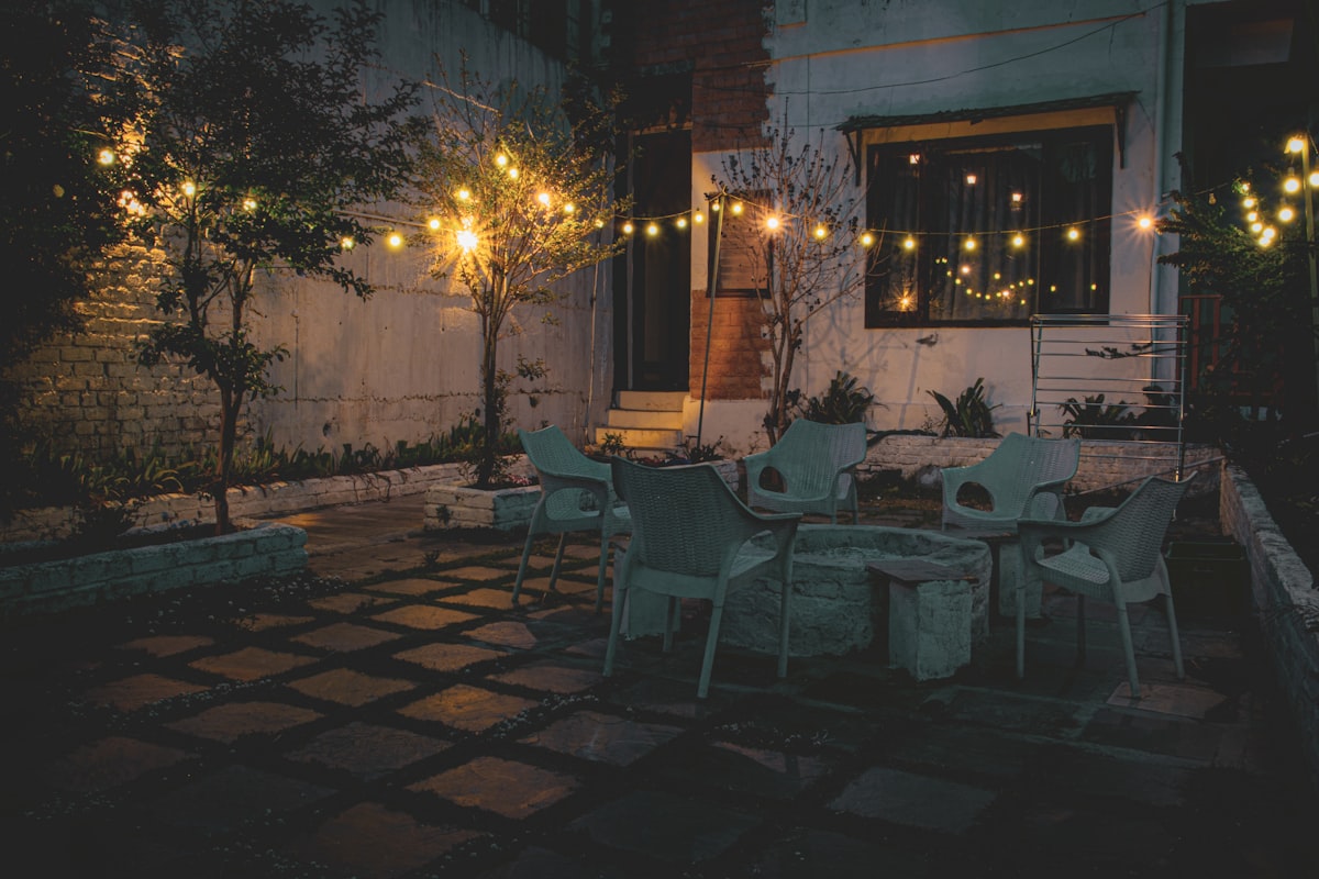 Patio with table, chairs, and string lights illuminated at dusk