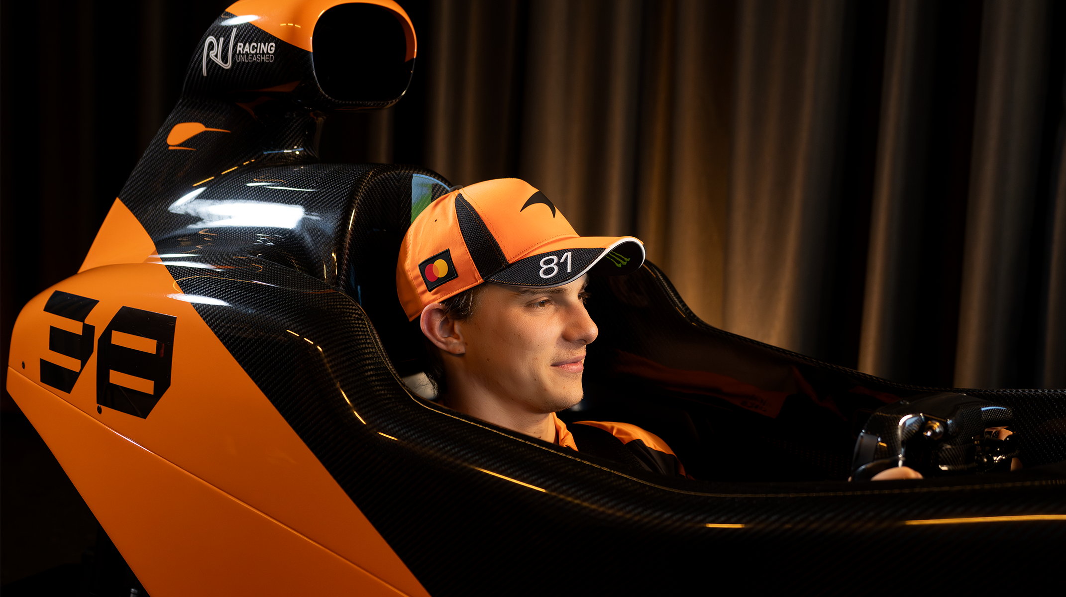 McLaren Formula 1 Team Driver Lando Norris with the McLaren Racing Motion Simulator by Racing Unleashed and the McLaren F1 Team race car at the McLaren Technology Center (MTC) in Woking, UK.