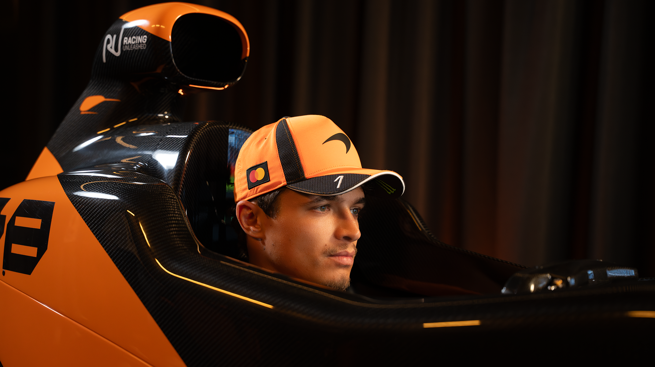 McLaren Formula 1 Team Driver Lando Norris with the McLaren Racing Motion Simulator by Racing Unleashed and the McLaren F1 Team race car at the McLaren Technology Center (MTC) in Woking, UK.