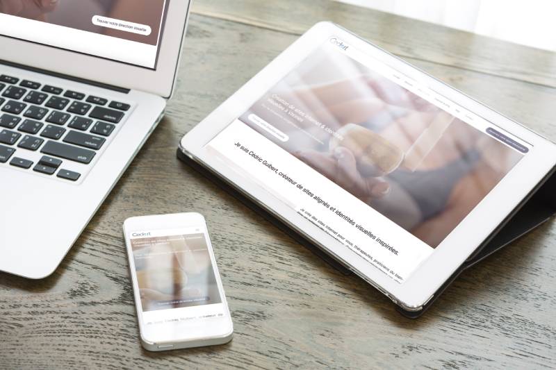 Ordinateur portable, tablette et smartphone affichant le site Cedart Studio sur une table en bois.