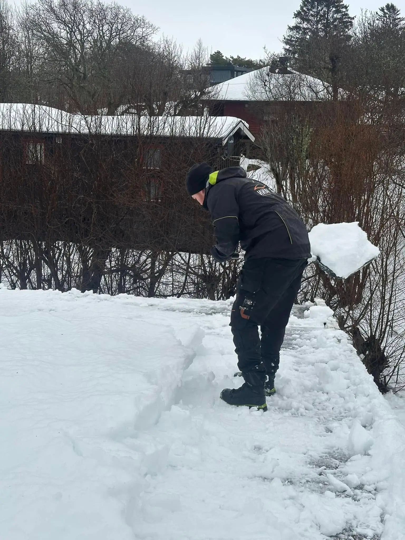 En som måker snø på et tak.