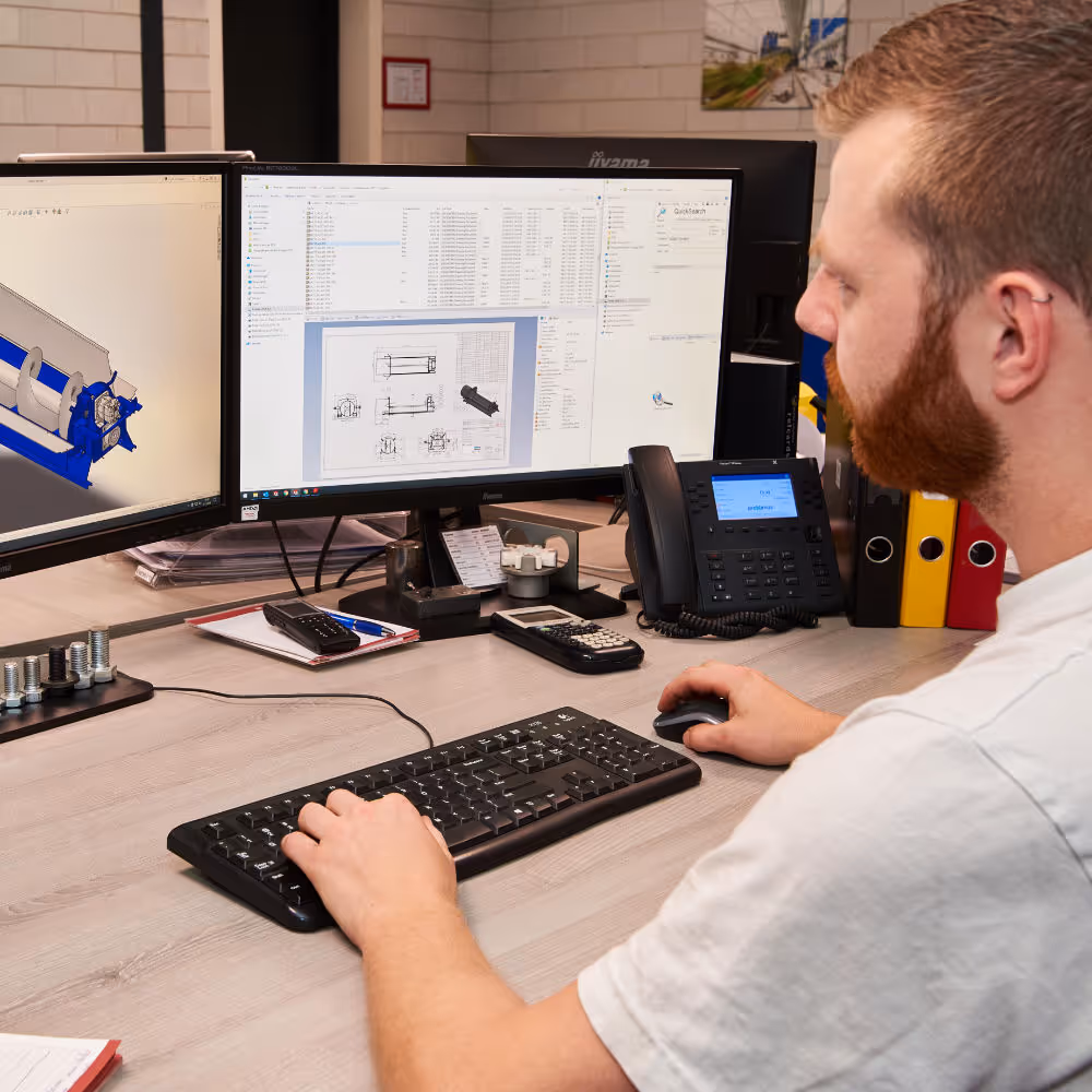 Medewerke van Heecon werkt aan bureau voor een computerscherm