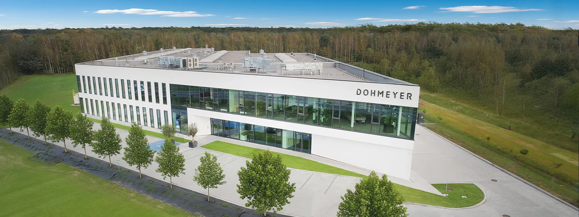 A drone picture of Dohmeyer Construction HQ in Poland, with clean parking lot, saplings planted around and lush greenery around.