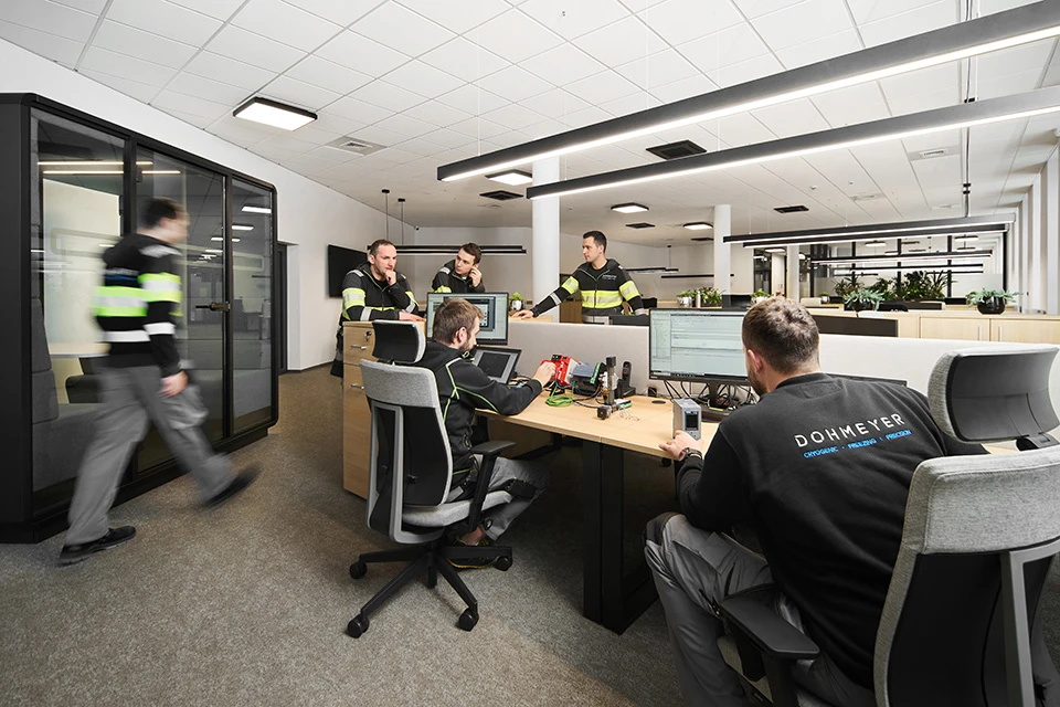 Automation department with people standing around desks, discussing technical challenges