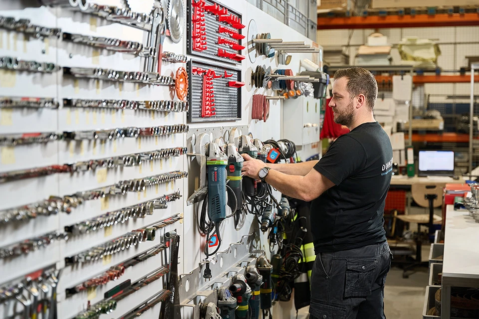 Workshop worker checking tools hanged on wall rack
