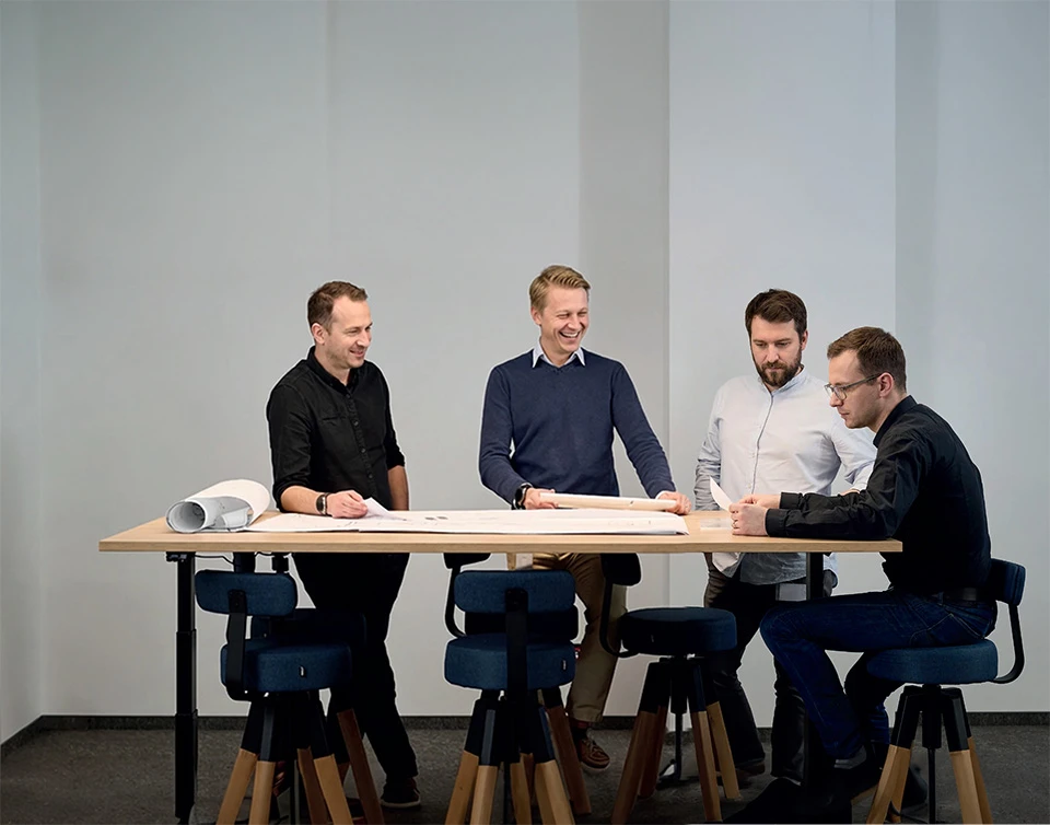engineers sitting at desk, talking about projects, smiling, laughing and discussing