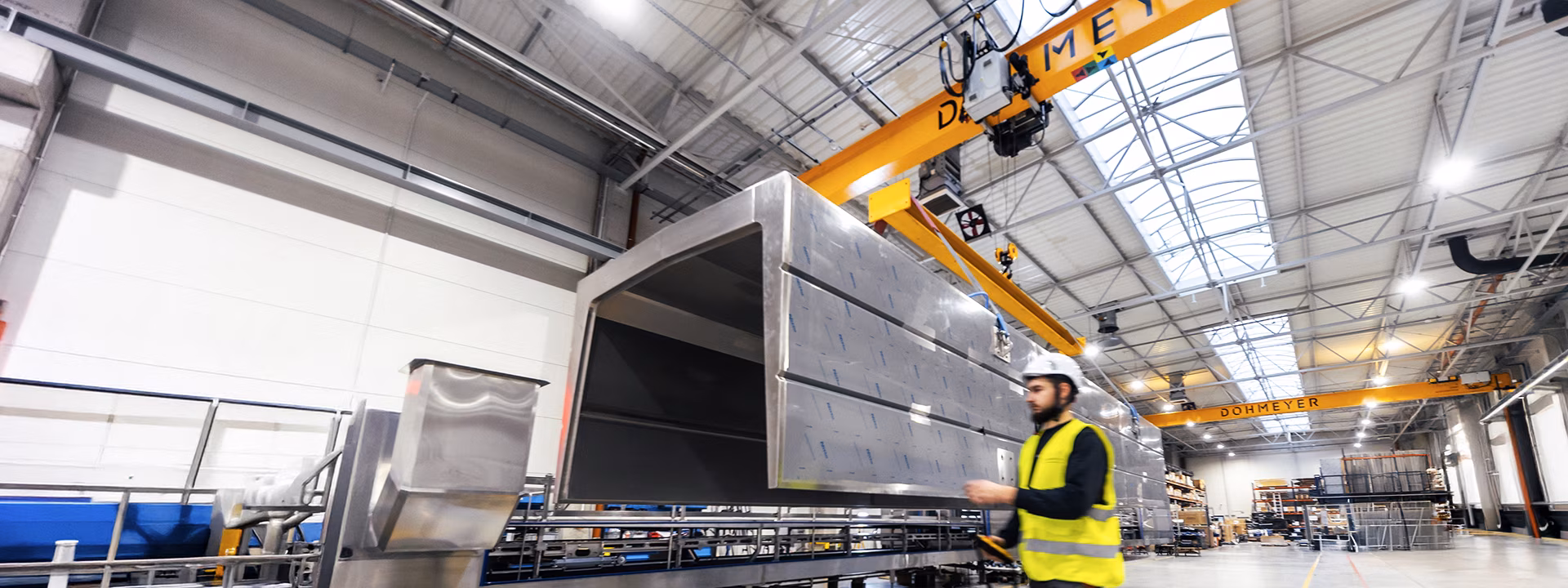 View of Dohmeyer workshop with an engineer operating an overhead crane to transport element of cryogenic tunnel