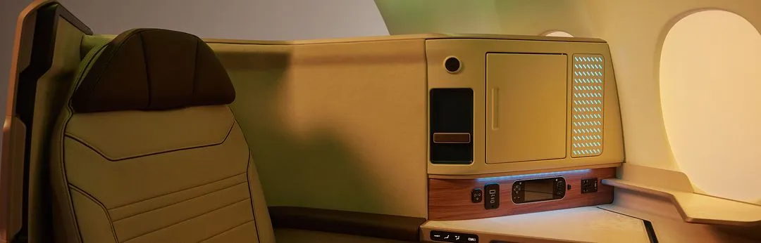 The interior of an airplane with a computer on the desk.