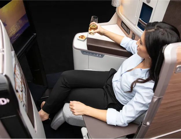 A woman sitting on an airplane holding a glass of wine.