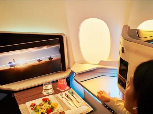 A woman sitting in an airplane watching a television.