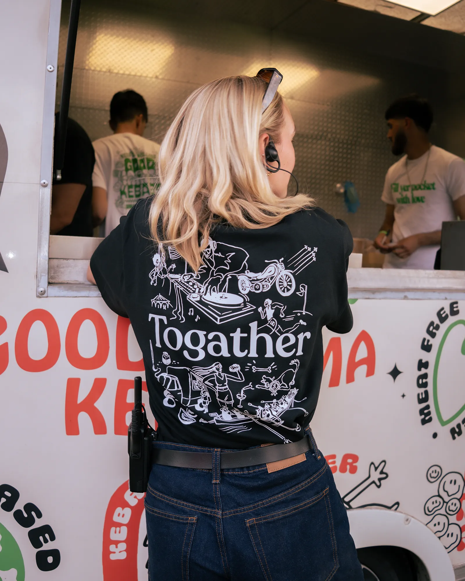 An employee of Togather, wearing a branded t-shirt, leaning on a food truck