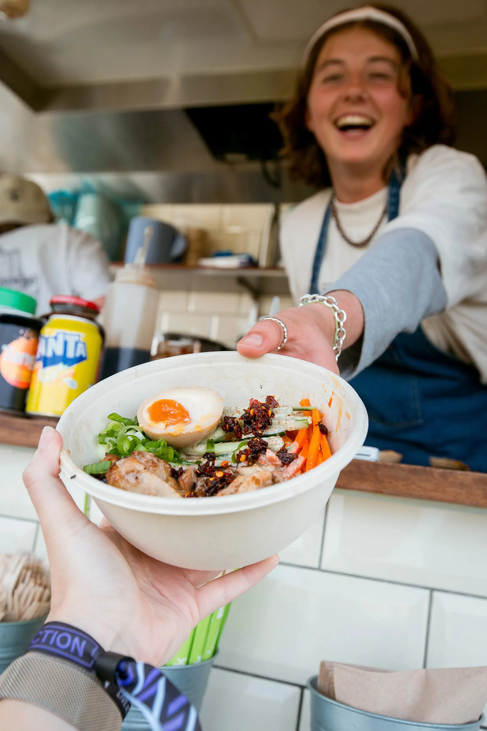 A woman serving a bowl of noodles from a food truck