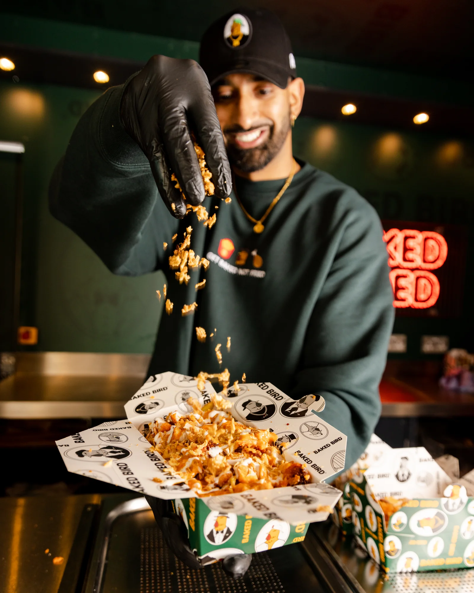 A man sprinkling garnish on a dish of baked chicken in the Baked Bird food truck